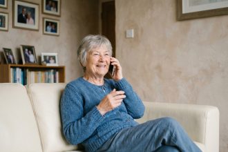 Femme âgée souriante utilisant un téléphone dans une résidence senior