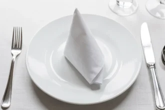 Serviette blanche pliée en cône posée sur une assiette